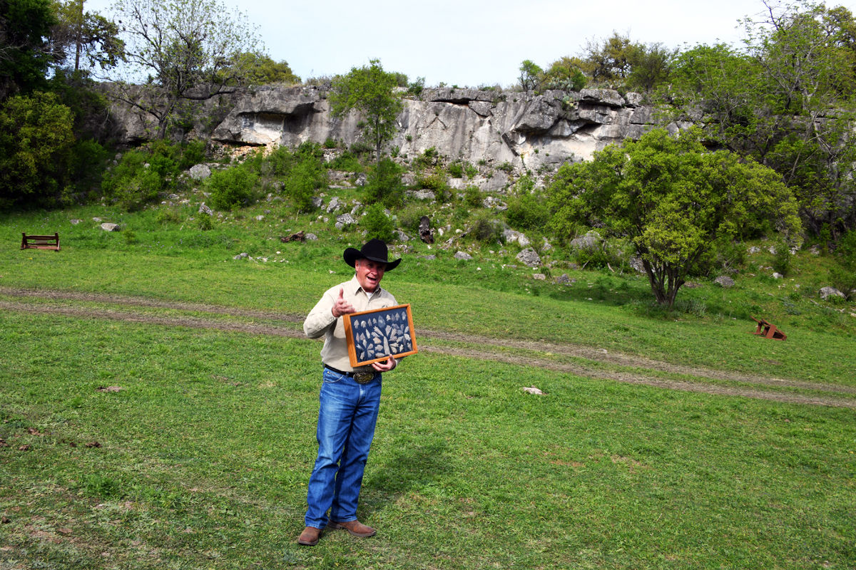 260 Chuck Knibbe with ancient Indian artifacts. In background is buffalo jump site on his ranch.JPG